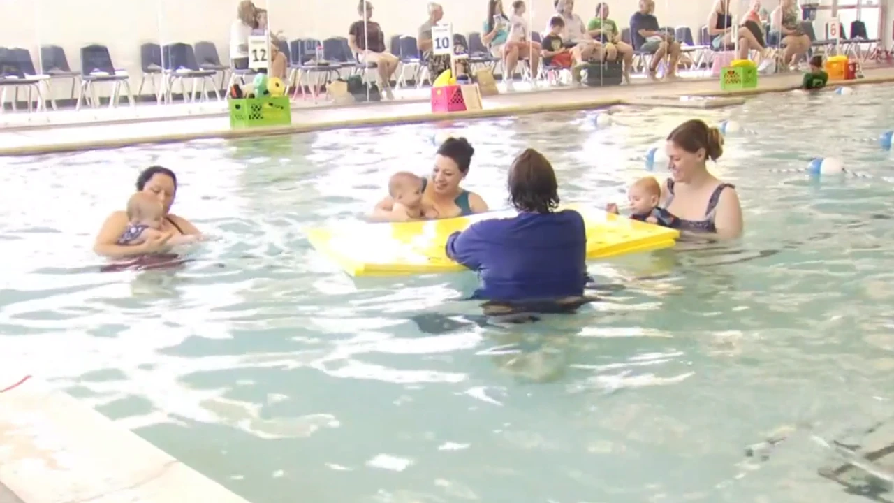 Trainers give swim lessons to babies at Miller Swim School 